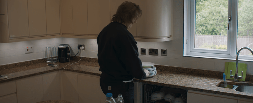 Lewis Capaldi stacks dishes in the kitchen of his former home