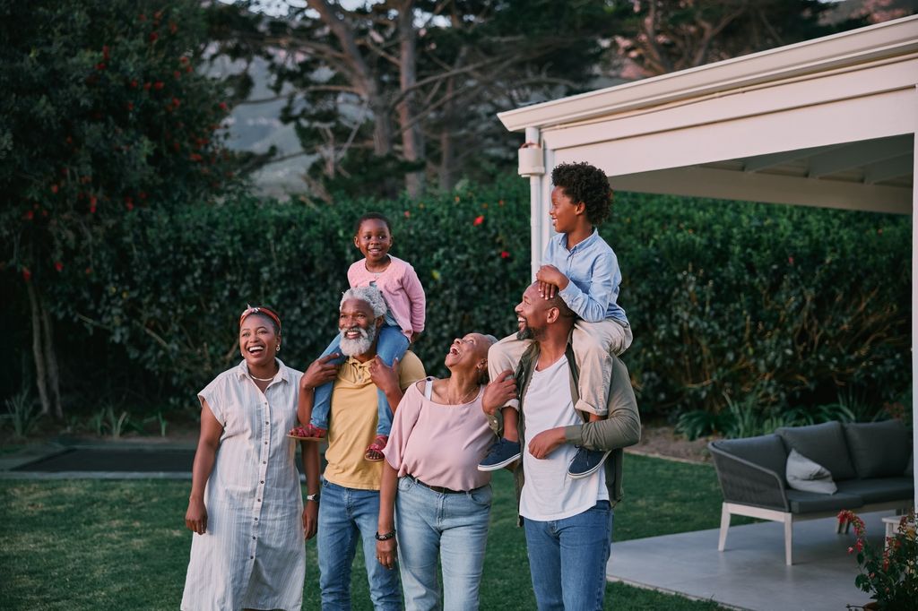 Kids, parents and grandparents together at a holiday home while outside in the garden at sunset