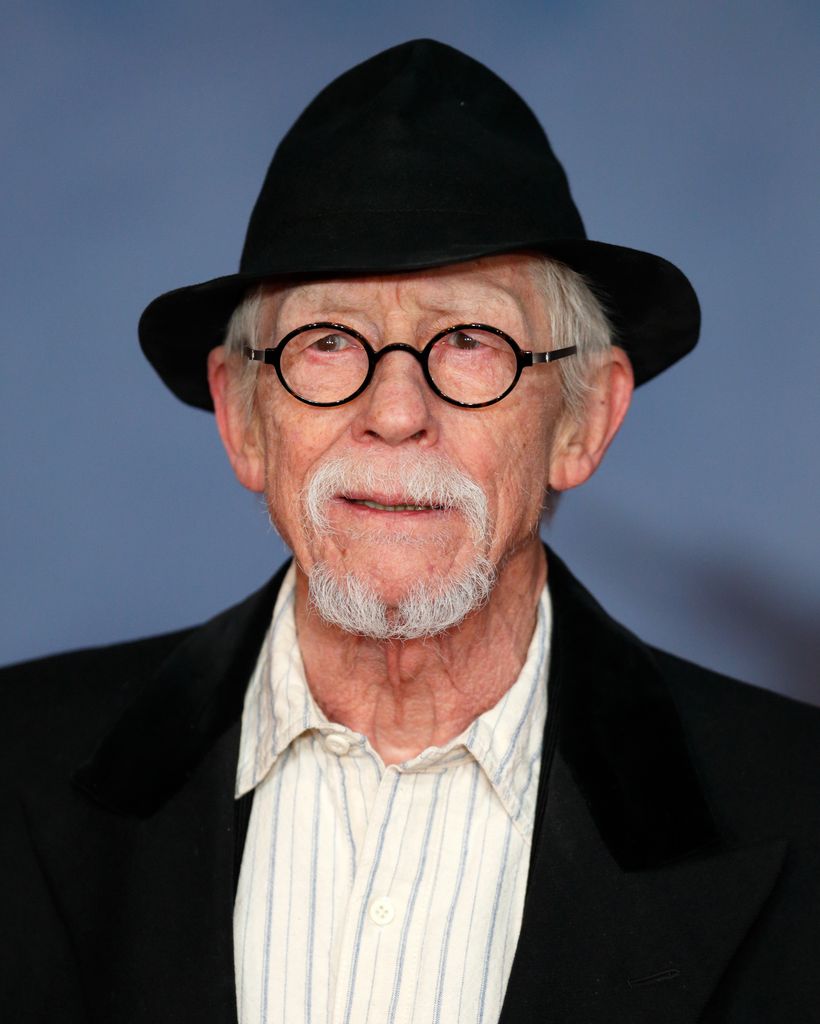 John Hurt in a black coat and hat