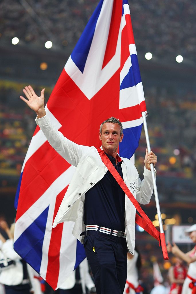 Mark Foster waving to crowd while carrying the Union Jack flag