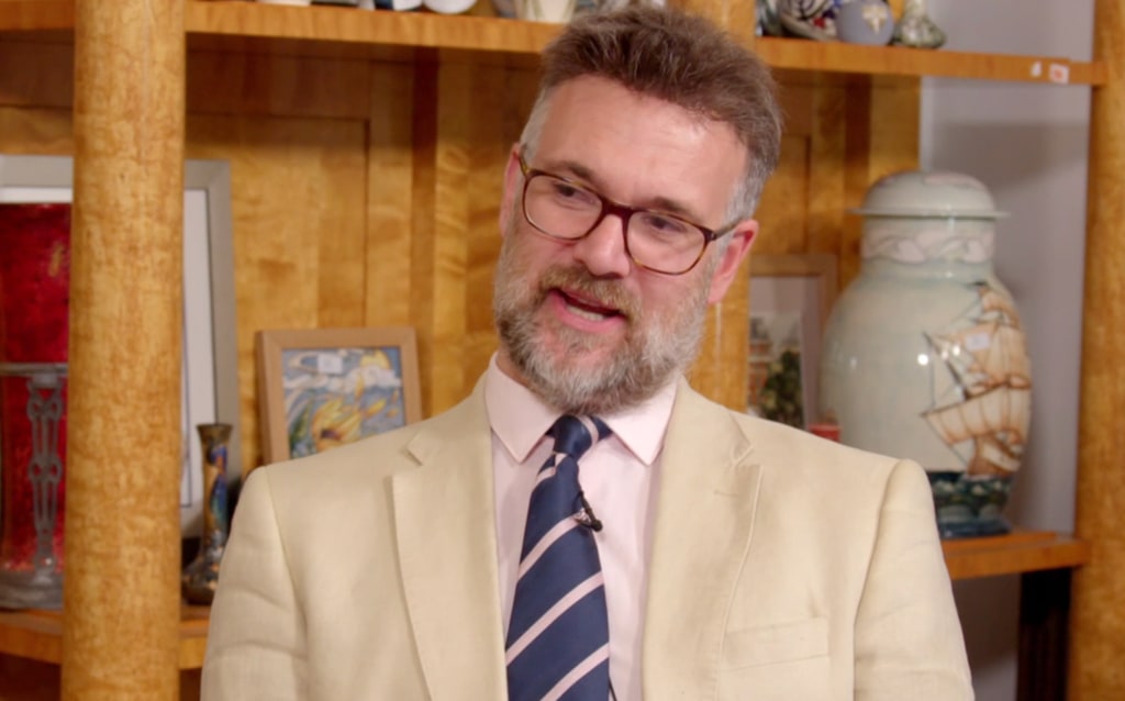 man in white suit with glasses