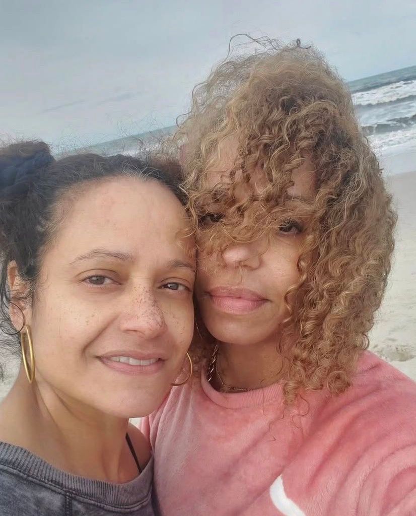 Two women standing behind ocean backdrop