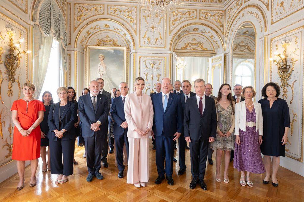 Princesse Charlene en costume rose en ligne de personnes au palais