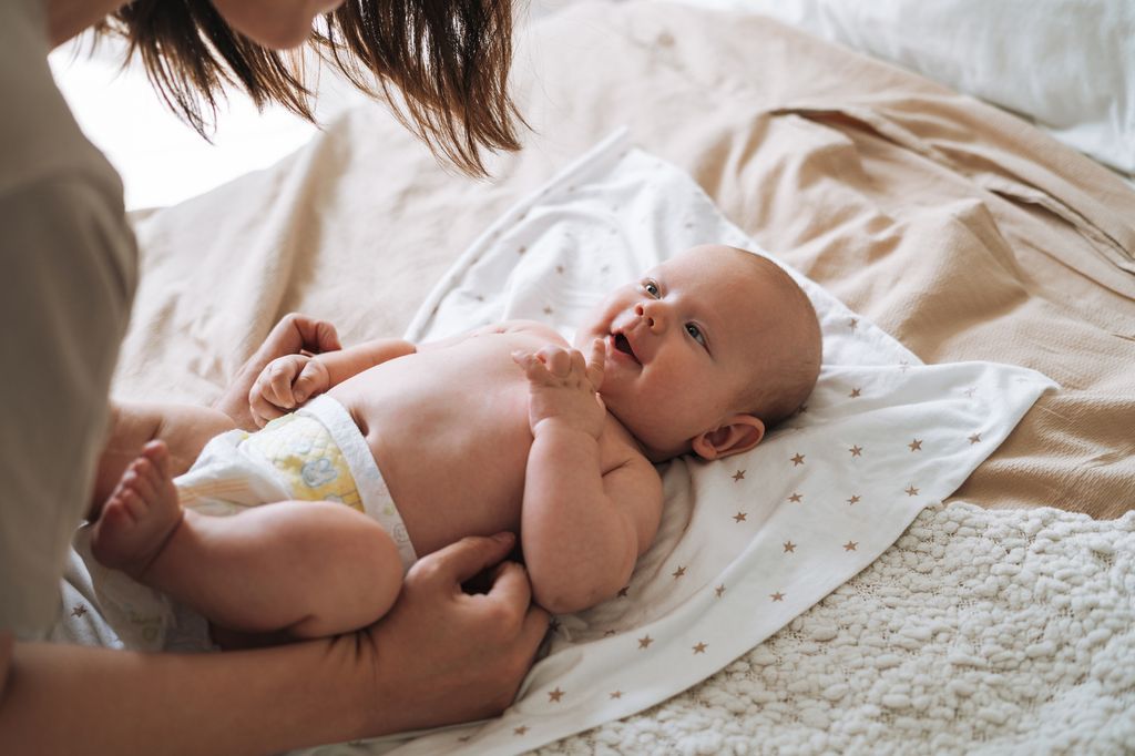 Adult woman young mother with 2-3 month baby boy lying on white blanket at home