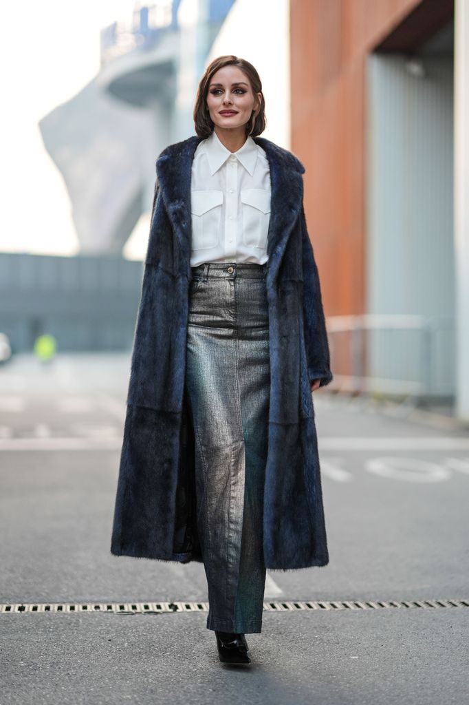 Olivia Palermo wears a luxurious navy fur coat with metallic details in the skirt, giving it an edgy elegance. The white blouse adds a classic touch, while the metallic skirt brings a modern twist. This look is perfect for a stylish snow day outing