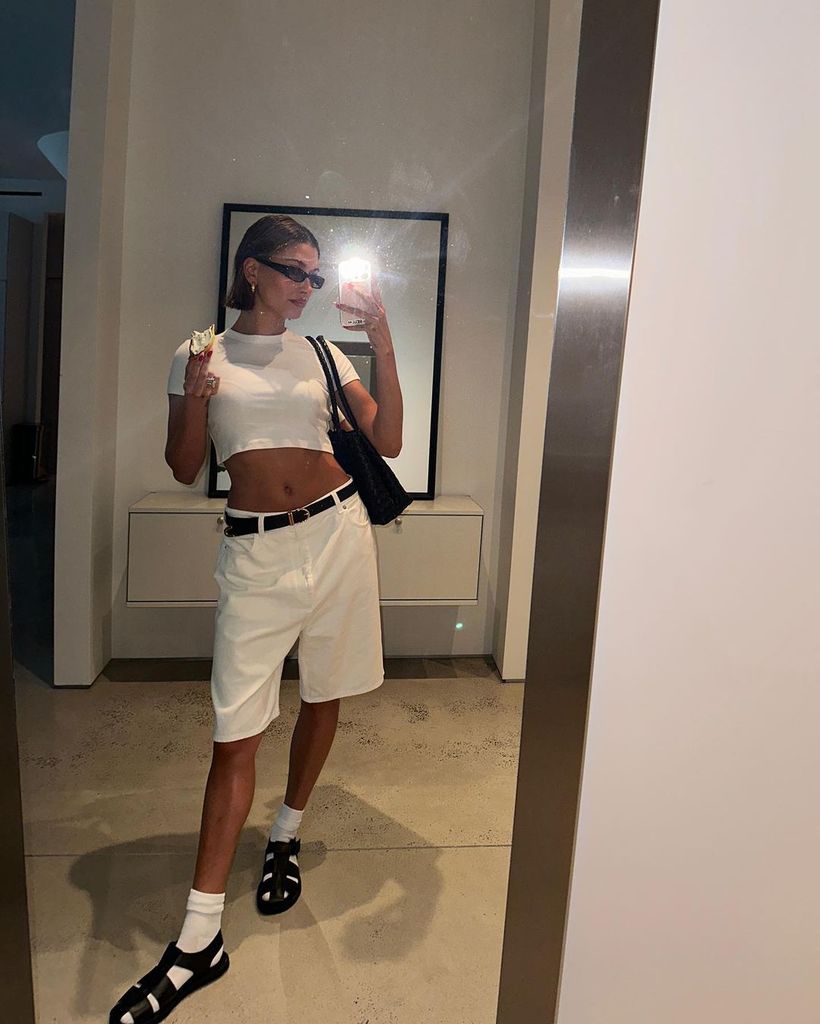 Hailey Bieber wears white shorts, t shirt and socks with sandals in an Instagram post 