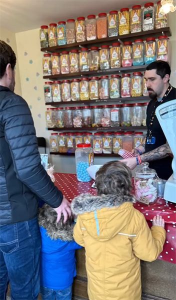A man stood with two children at a sweet shop counter