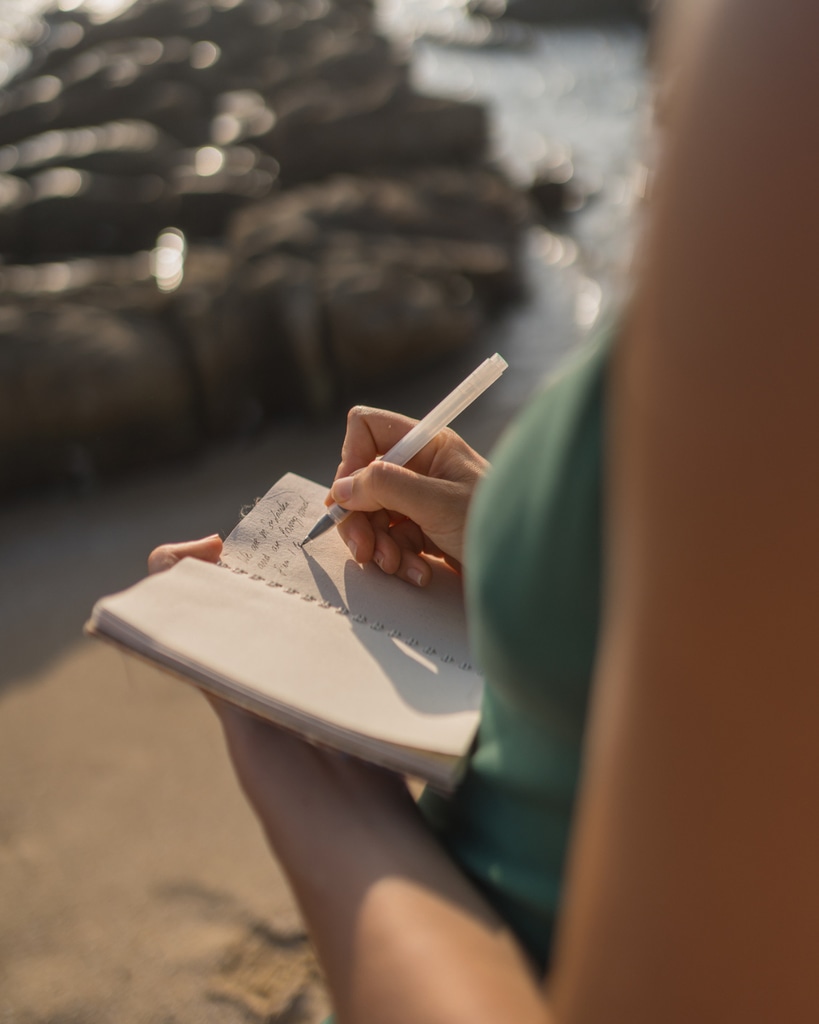 A woman writing a journal by the sea