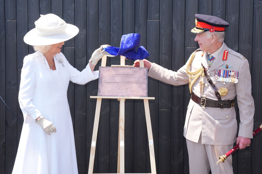 Queen Camilla and King Charles in military uniform unveiling a plaque