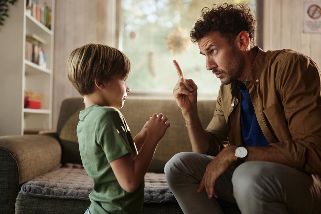 Single father scolding with his small son in the living room.