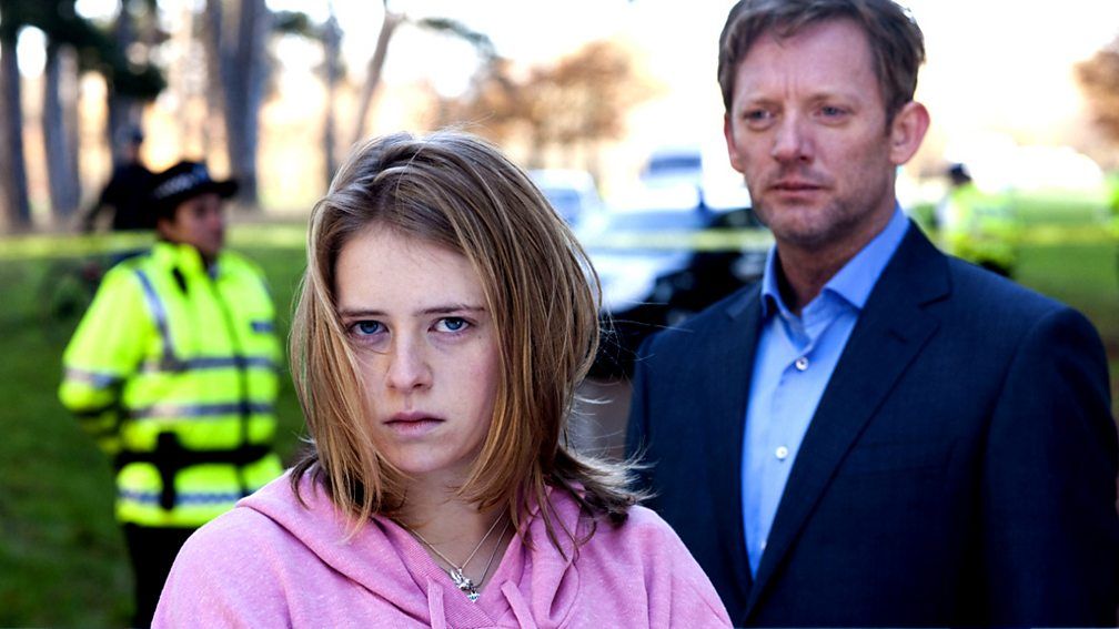 Young girl and man in suit standing in front of police tape