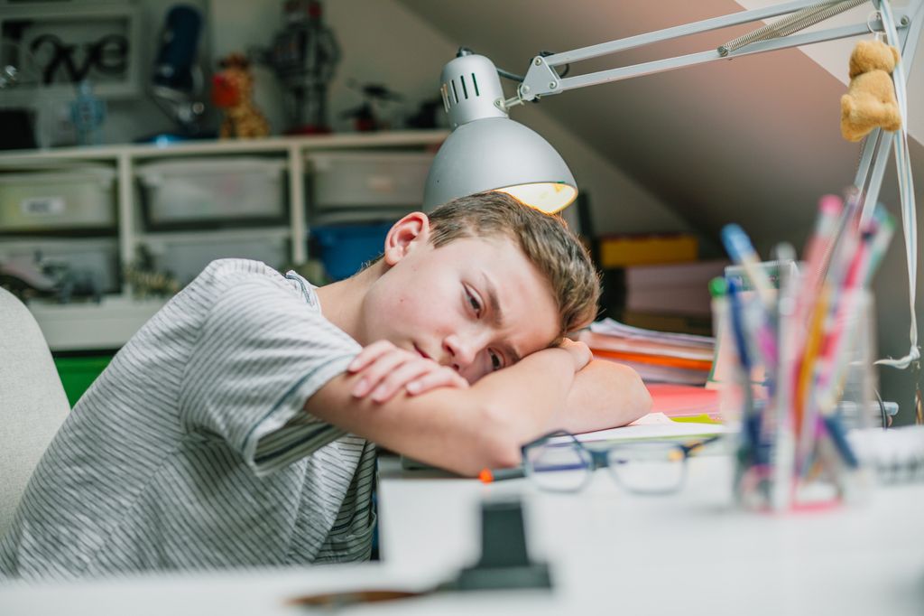 young boy leaning head on desk