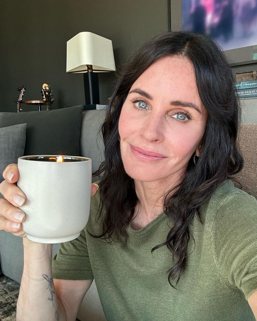Courteney Cox holds up a candle