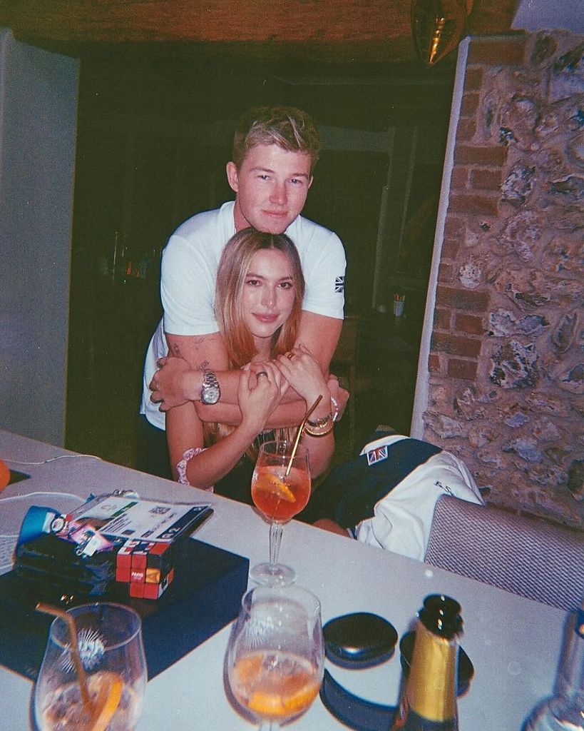 Harry Charles with his arms around Eve Jobs as they sit at dining table