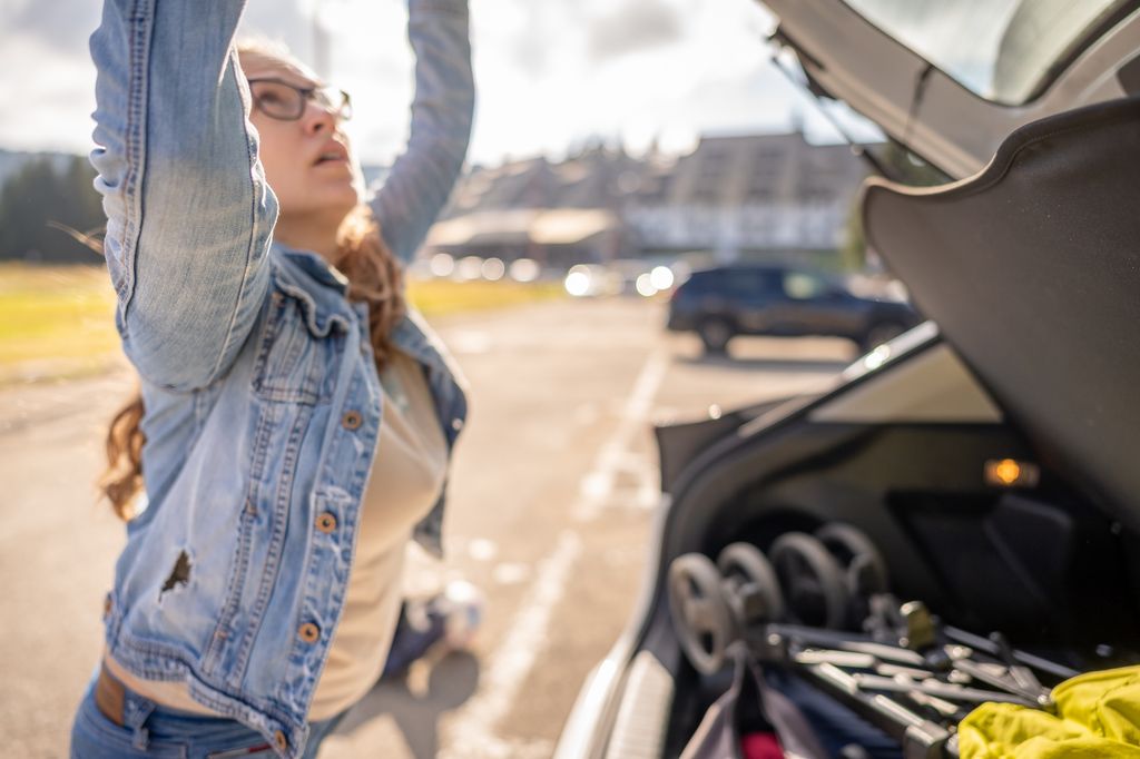 Woman preparing for a road trip, she is closing a car trunk