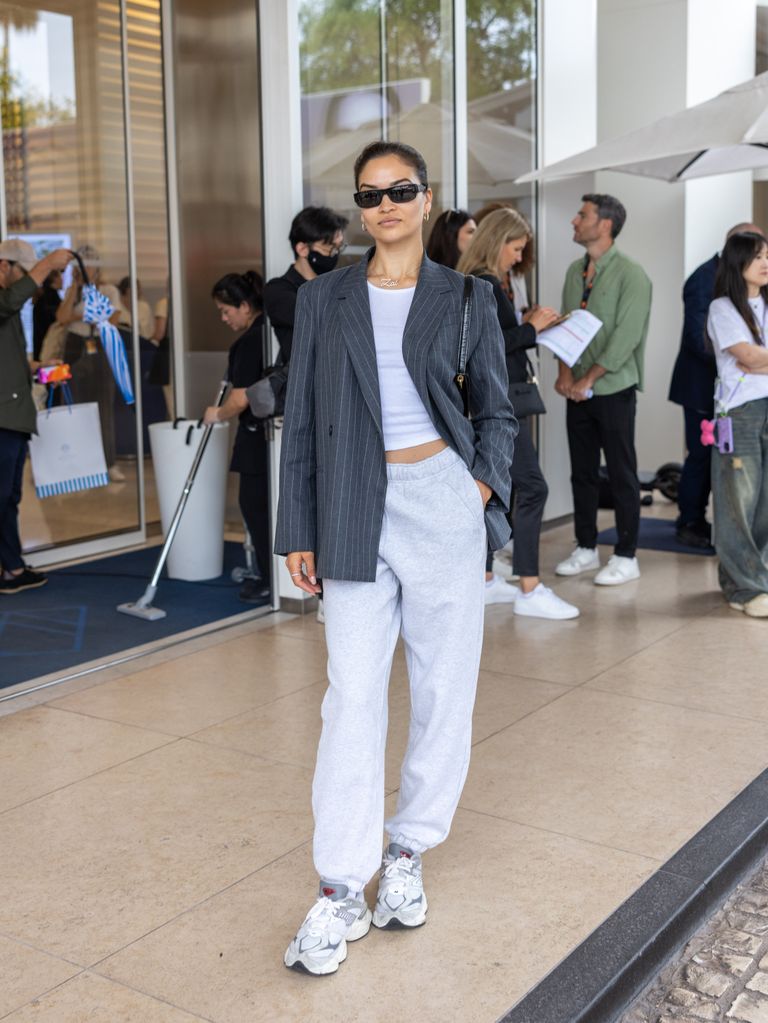 Shanina Shaik wears grey sweat pants and a blazer while at The 77th Annual Cannes Film Festival