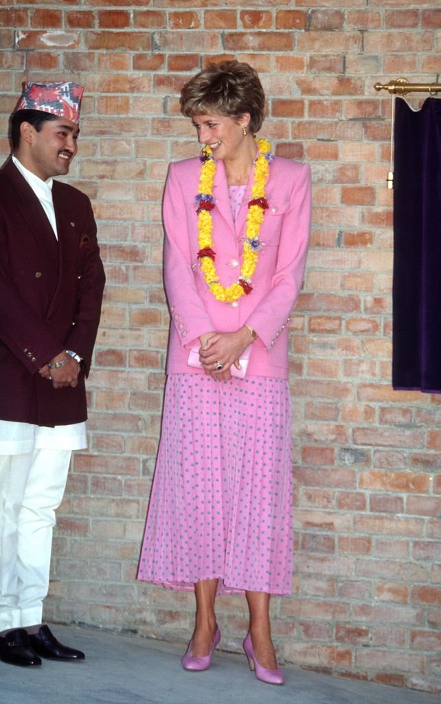 Putri Diana mengenakan gaun berwarna pink dengan polkadot biru dan jaket berwarna pink karya Paul Costelloe