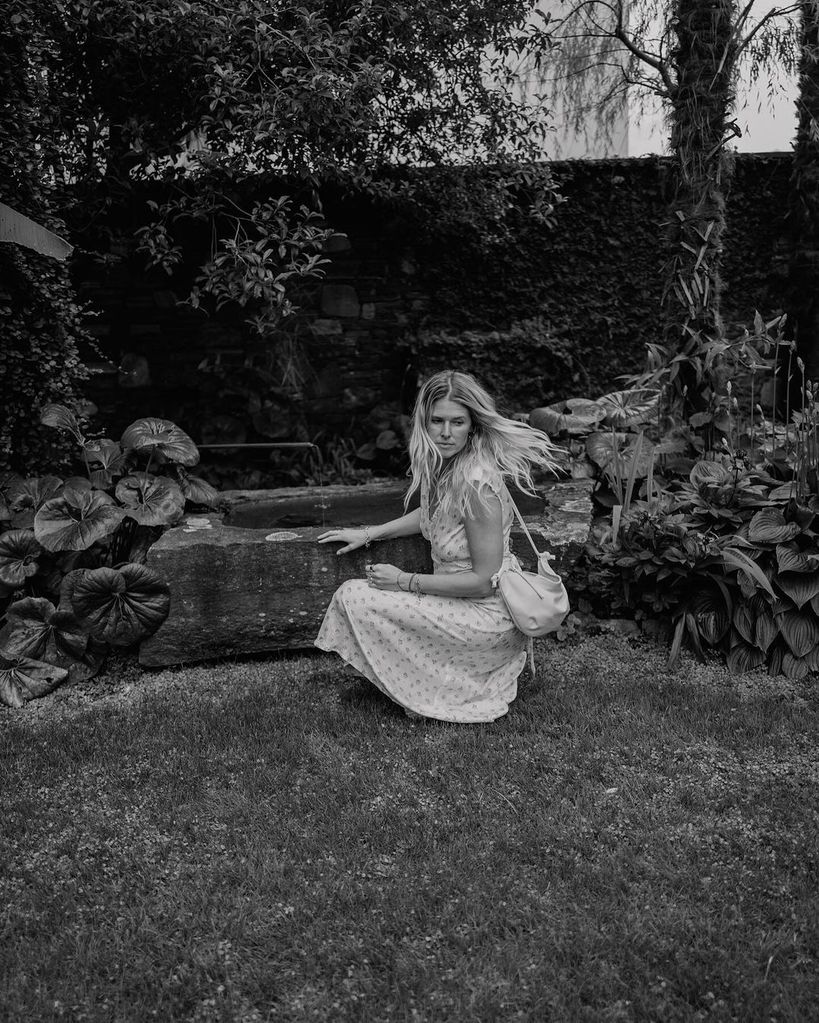 Sarah Wright Olsen crouches down near a well in Switzerland