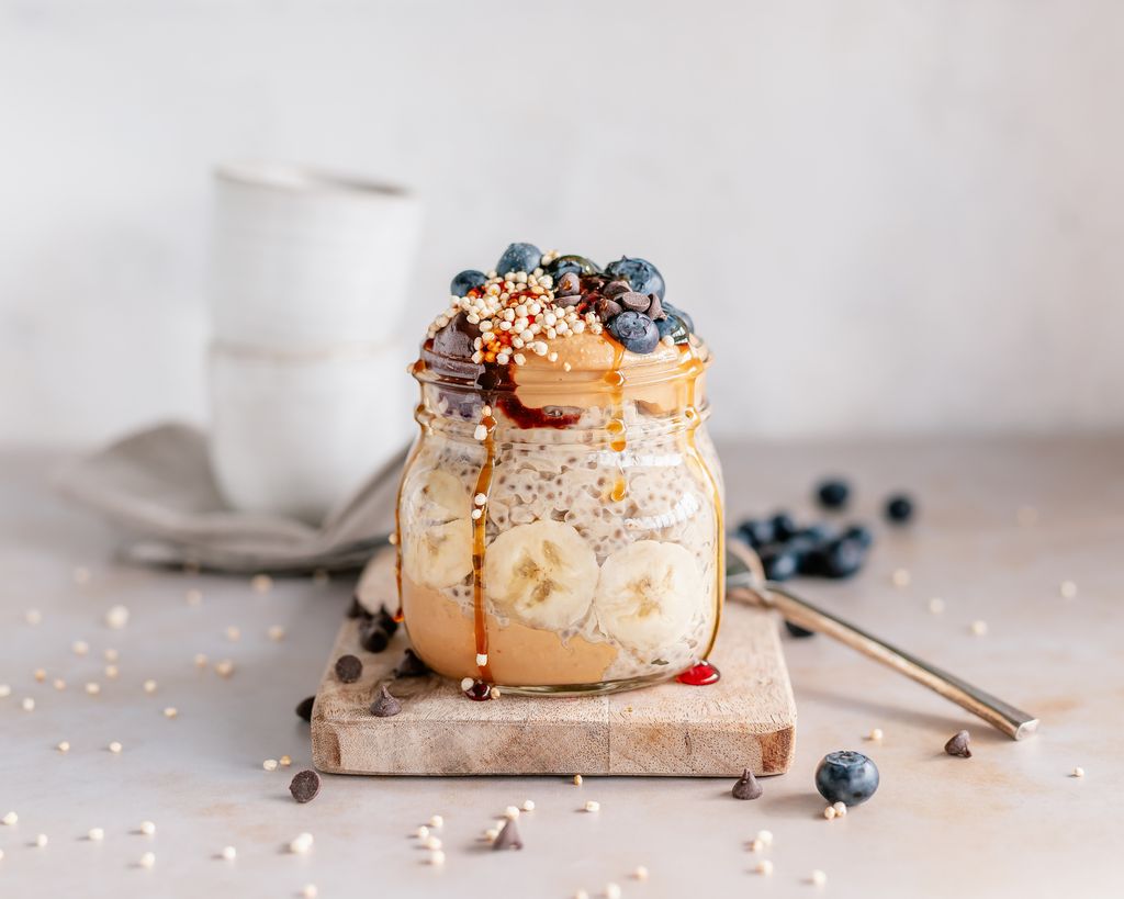 Close up of a jar filled with banana overnight oats served with peanut butter and a variety of toppings