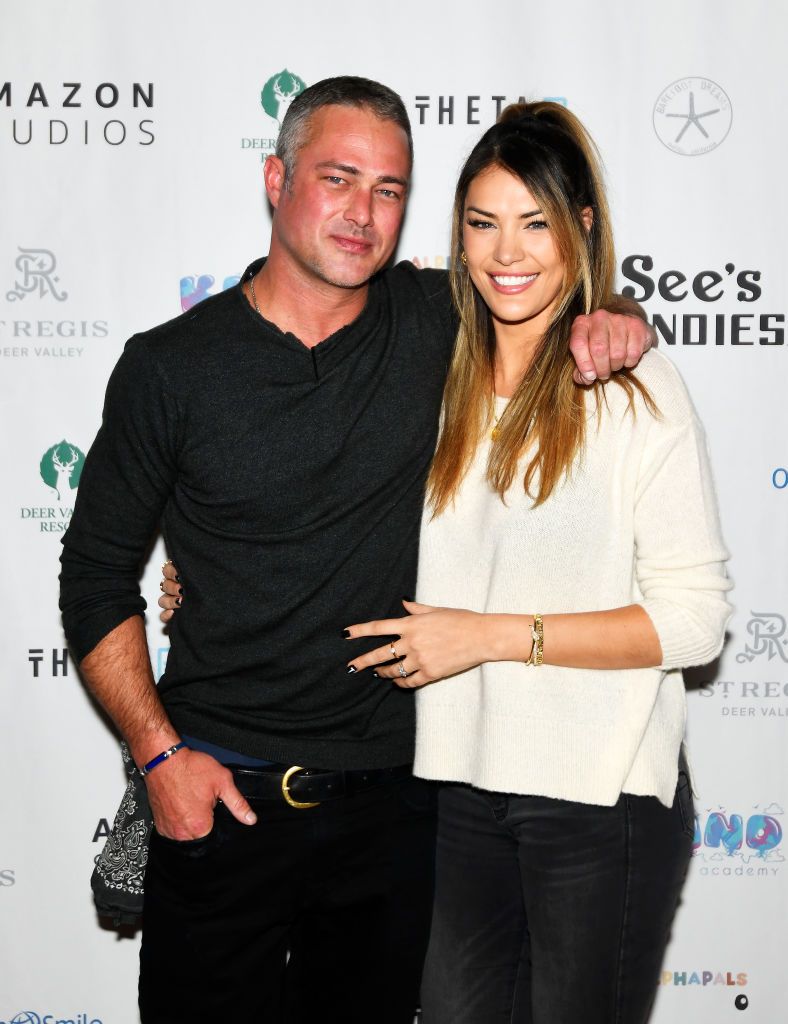 Ashley Cruger and Taylor Kinney cuddle up for a photo at a press event. 