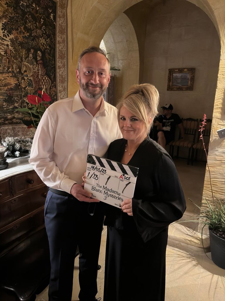 Sally Lindsay and Steve Edge hold up clapperboard on set