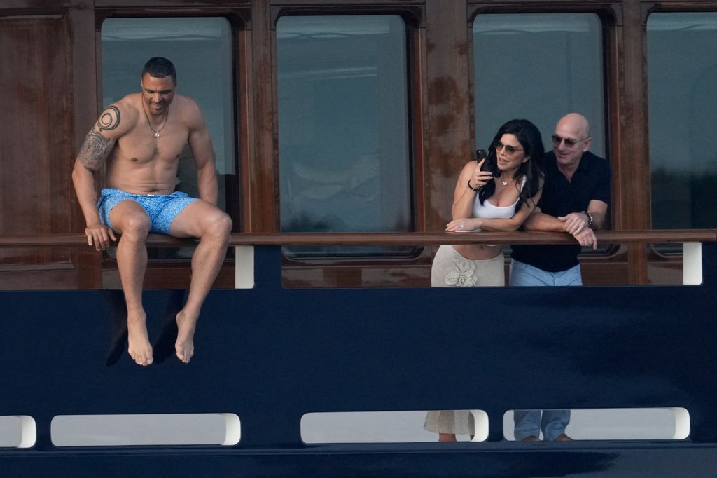 Jeff Bezos and Lauren Sanchez watch as shirtless man gets off the yacht