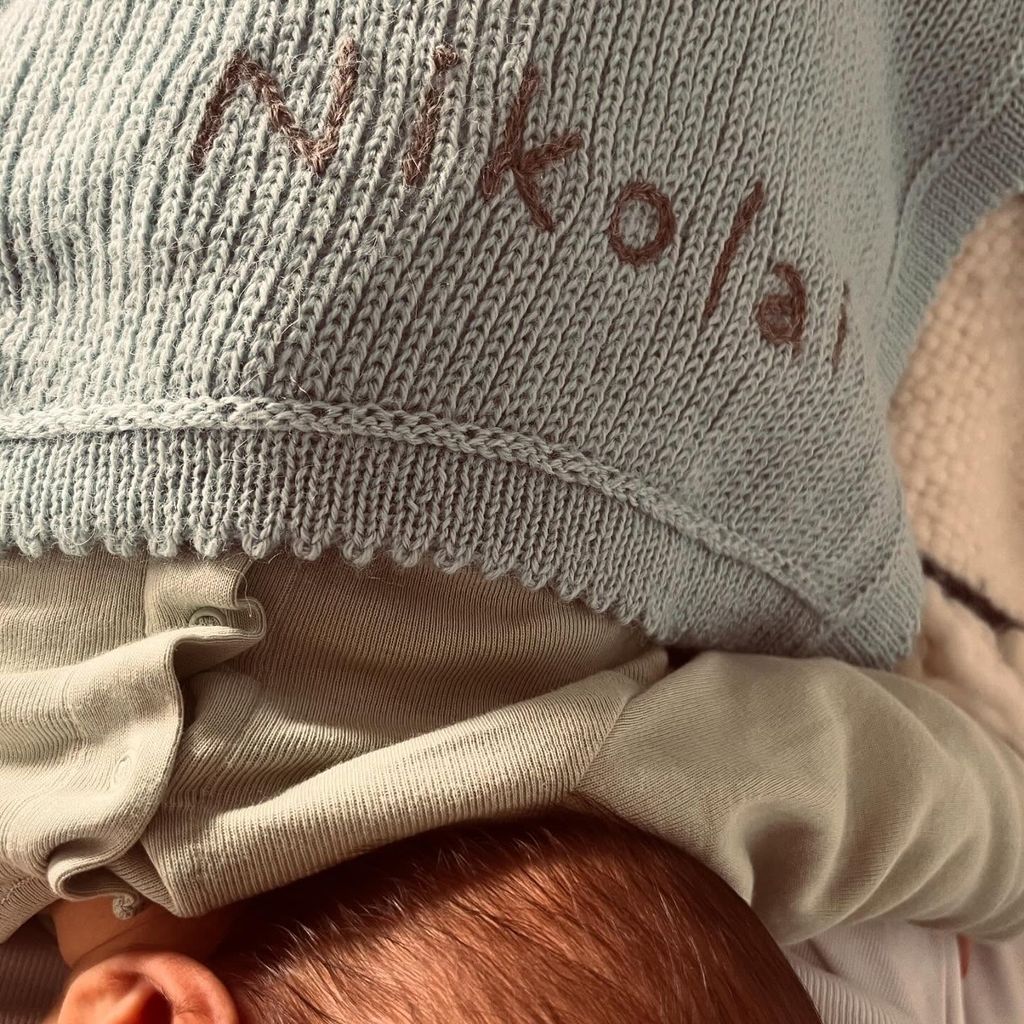 newborn under blanket with 'nikolai; stitched on