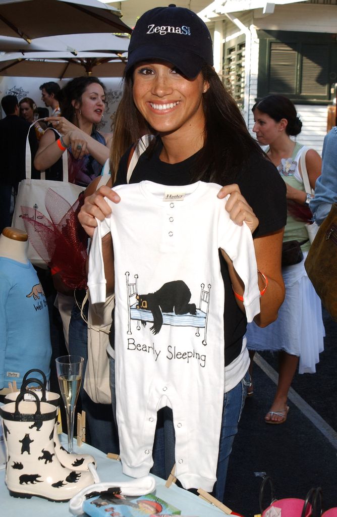 Meghan Markle smiling holding up a babygrow