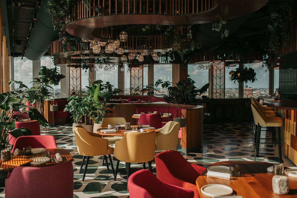 Interior of Selva, a Latin American restaurant in Amsterdam, featuring lush rainforest-inspired décor and panoramic 360-degree city views from the 24th floor of the nhow Amsterdam RAI hotel