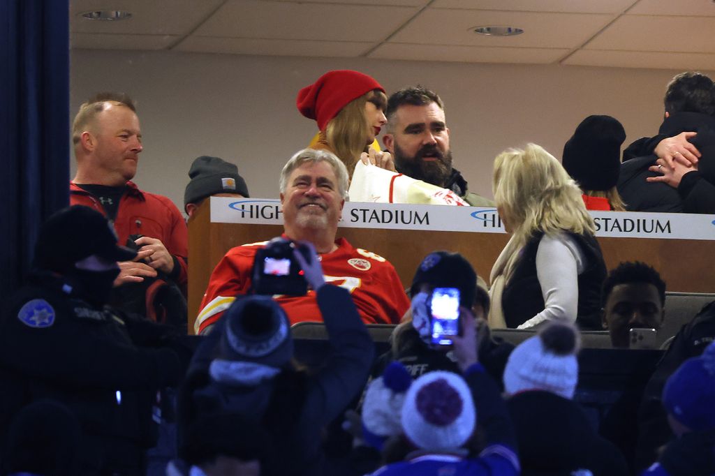 Singer-songwriter Taylor Swift and Jason Kelce #62 of the Philadelphia Eagles talk in a suite as fans take pictures prior to the AFC Divisional Playoff 