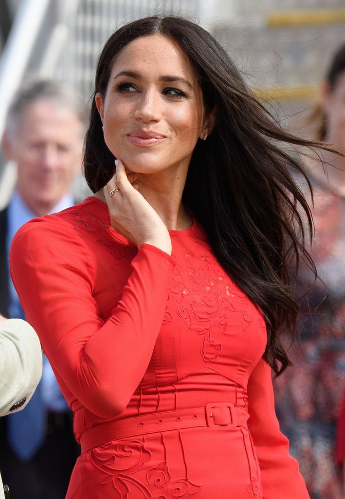 Meghan Markle smiling in a red dress