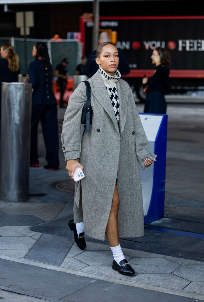 A guest wears grey oversized coat, turtleneck outside Tommy Hilfiger New York Fashion Week on September 08, 2024 in New York City.