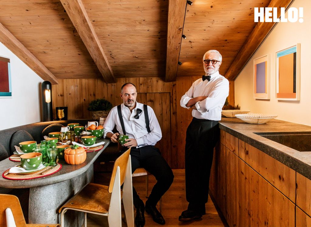Emmanuel is sat down in the kitchen and Josef is stood up with his arms crossed beside him