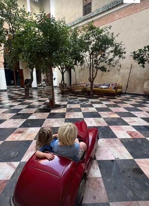 Two young children sat in a small red car