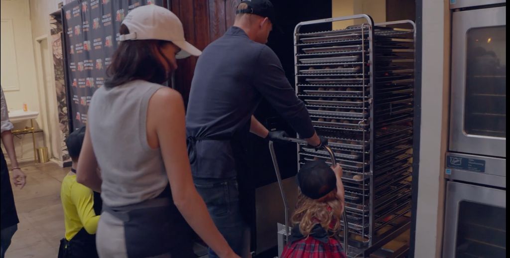 Prince Harry pushing a trolley of food with Princess Lili, Prince Archie and Meghan Markle