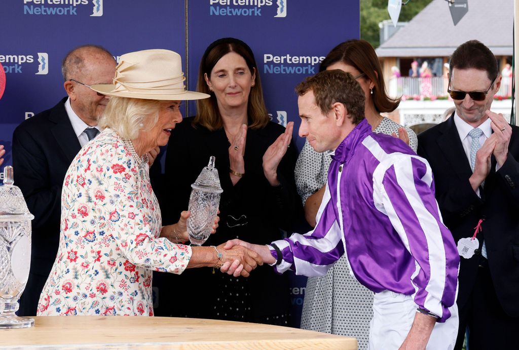 queen shaking ryan moore's hand and giving him trophy