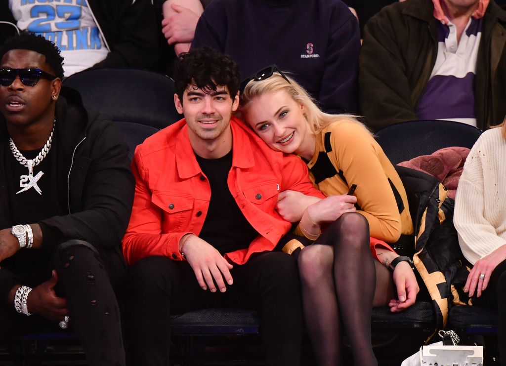 Joe Jonas in red jacket cuddling Sophie Turner pre divorce at  Sacramento Kings v New York Knicks game at Madison Square Garden