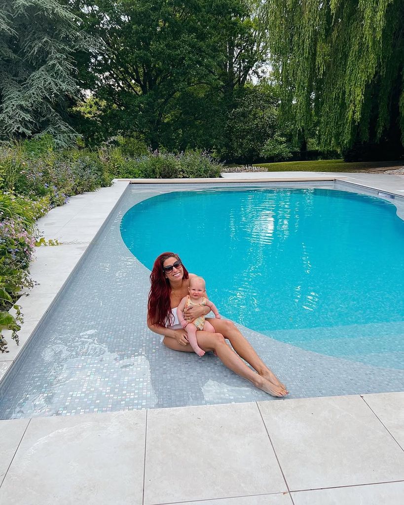 Stacey Solomon holding her daughter, Rose, while lying poolside