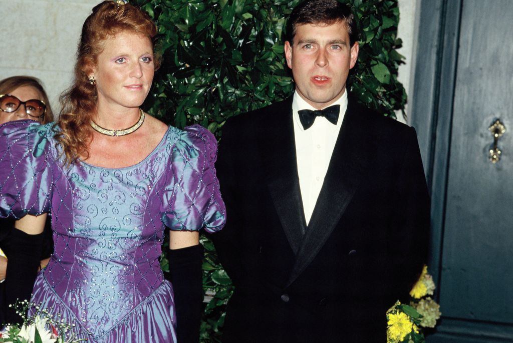 Sarah Ferguson wearing a purple dress and long black gloves next to Andrew Mountbatten-Windsor in a black and white bow tie suit
