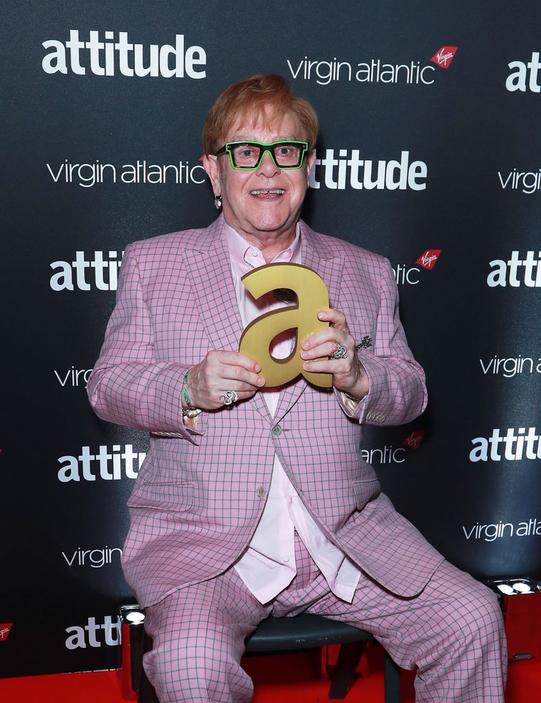 Elton John sitting down holding an Attitude Award