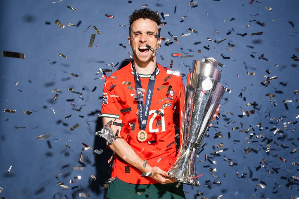 Diogo Jota holding a trophy with confetti around him