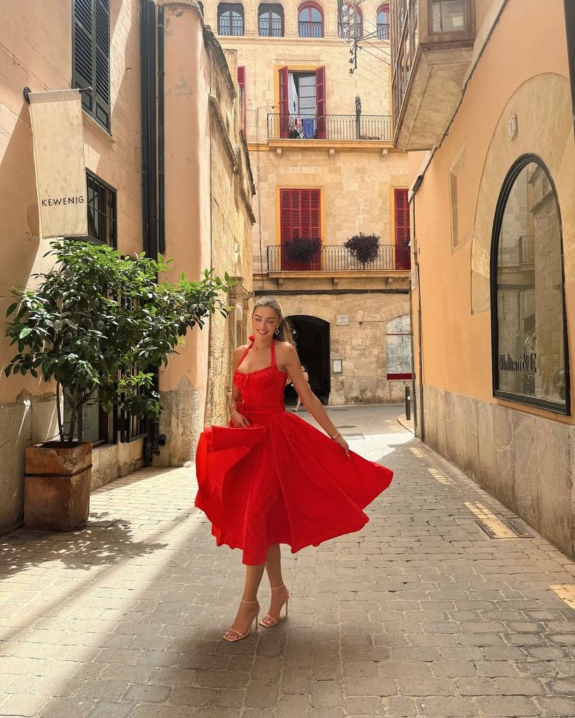 Zara McDermott sorri enquanto caminha pela rua com um vestido vermelho em Maiorca
