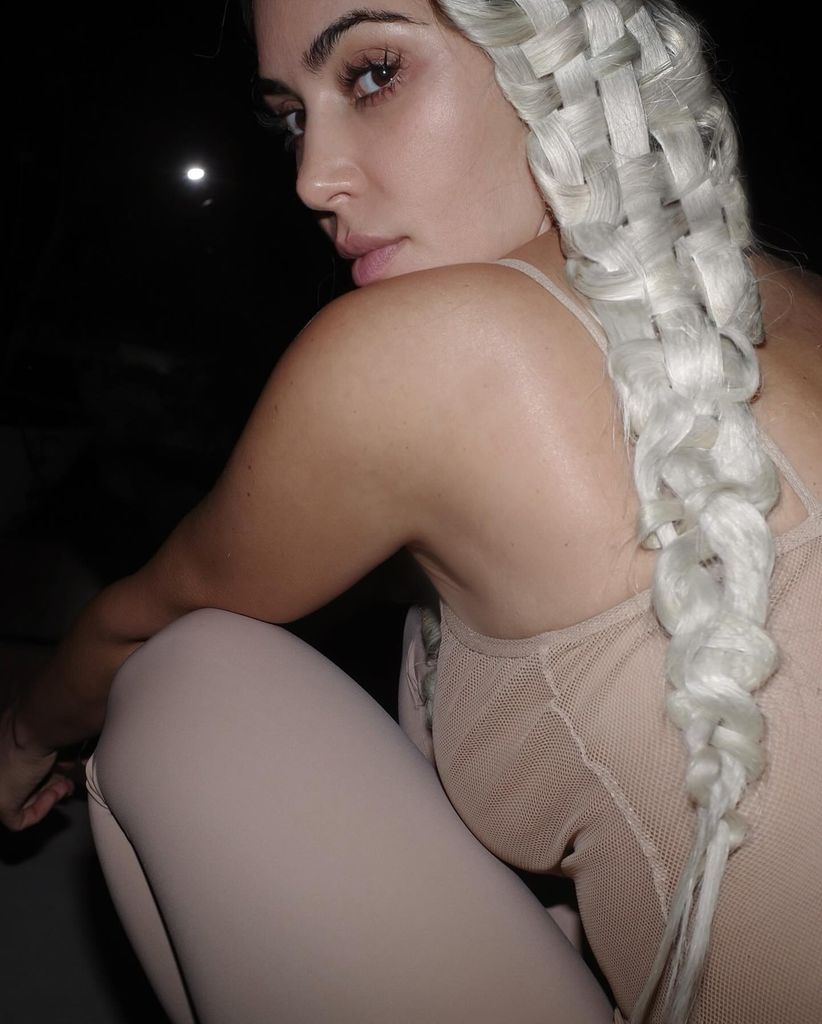 Kim Kardashian sitting on the ground with braided hair