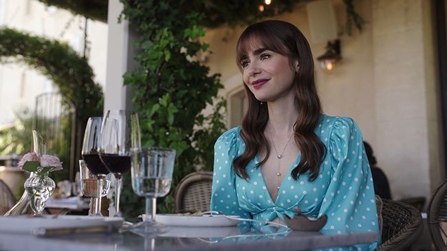 lily collins as emily cooper sits at dining table in emily in paris