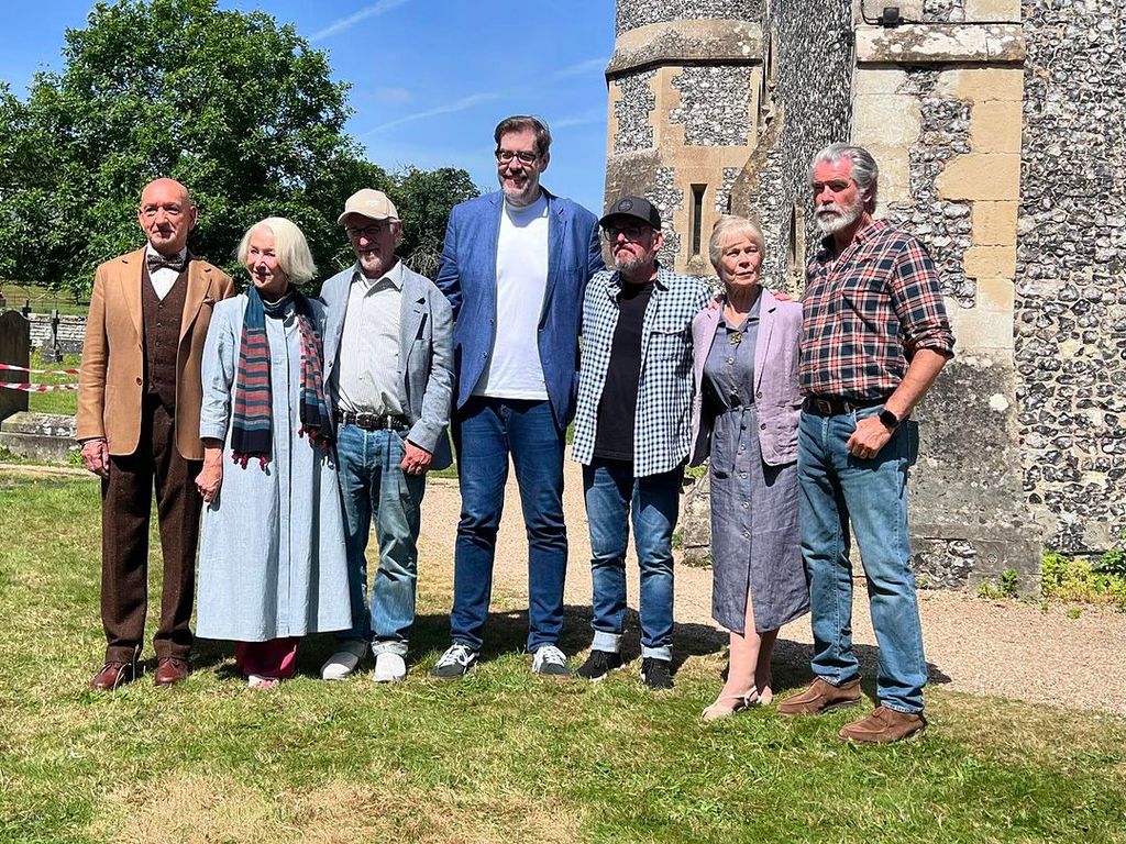 The cast of The Thursday Murder Club (Ben Kingsley, Helen Mirren, Celia Imrie, and Pierce Brosnan) on set with Richard Osman and Steven Spielberg