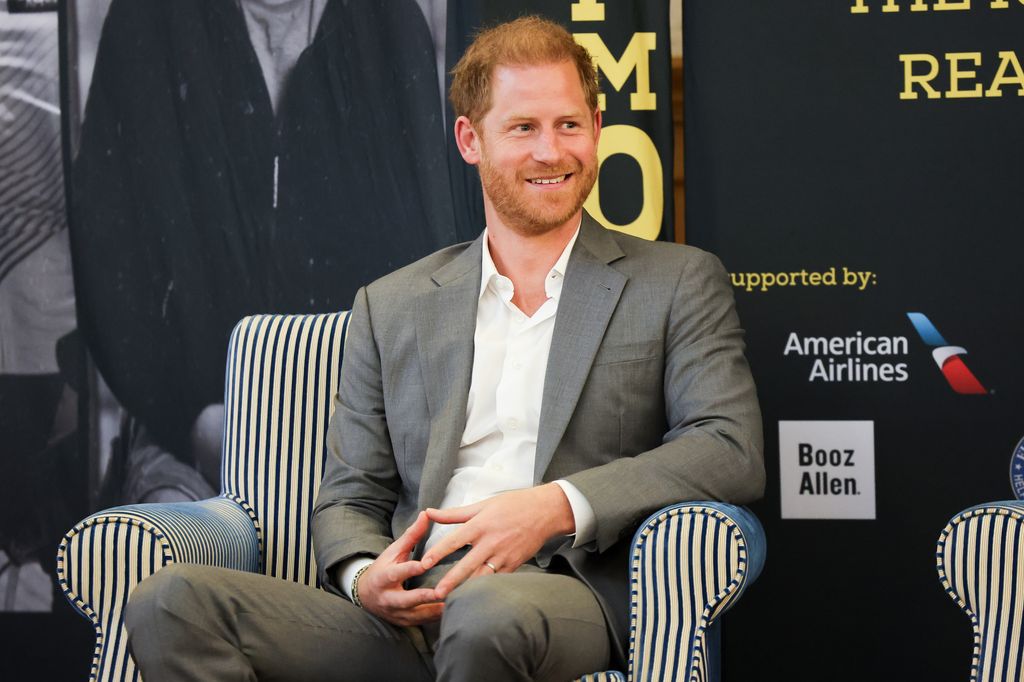 Prince Harry sitting in a chair while wearing a grey suit