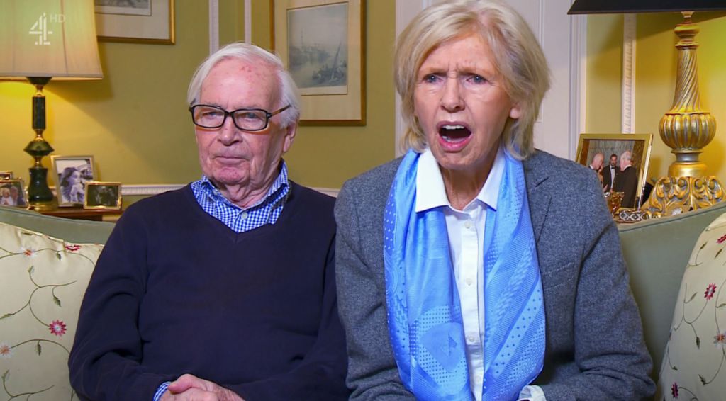 John and Beryl from Gogglebox in their living room; Beryl appears to be shocked with an open mouth