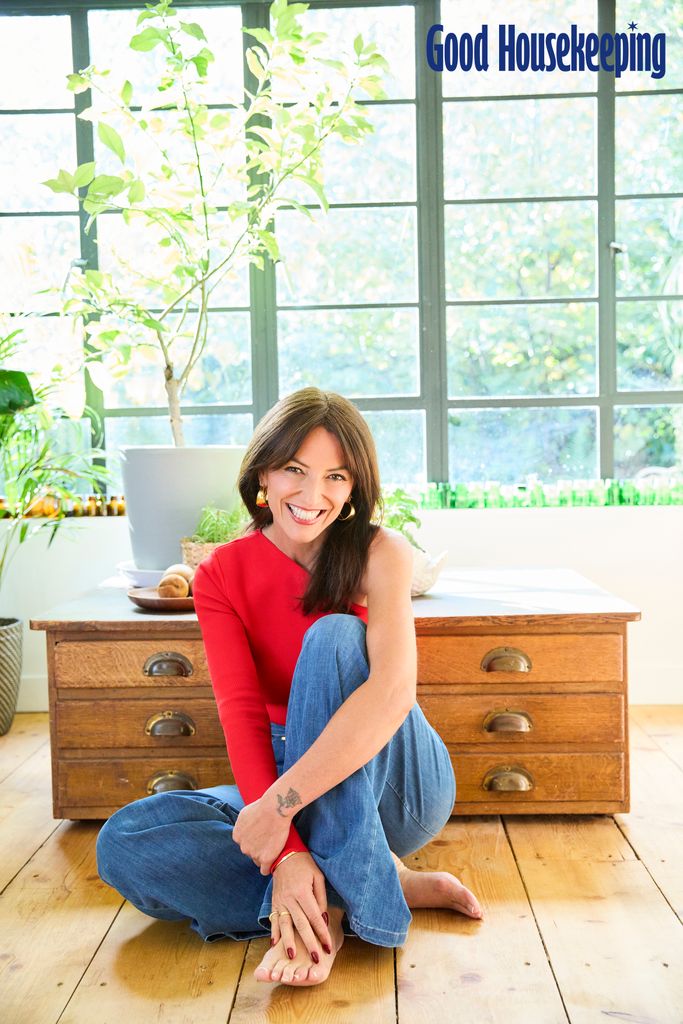 Davina McCall in red top and jeans sitting on the floor