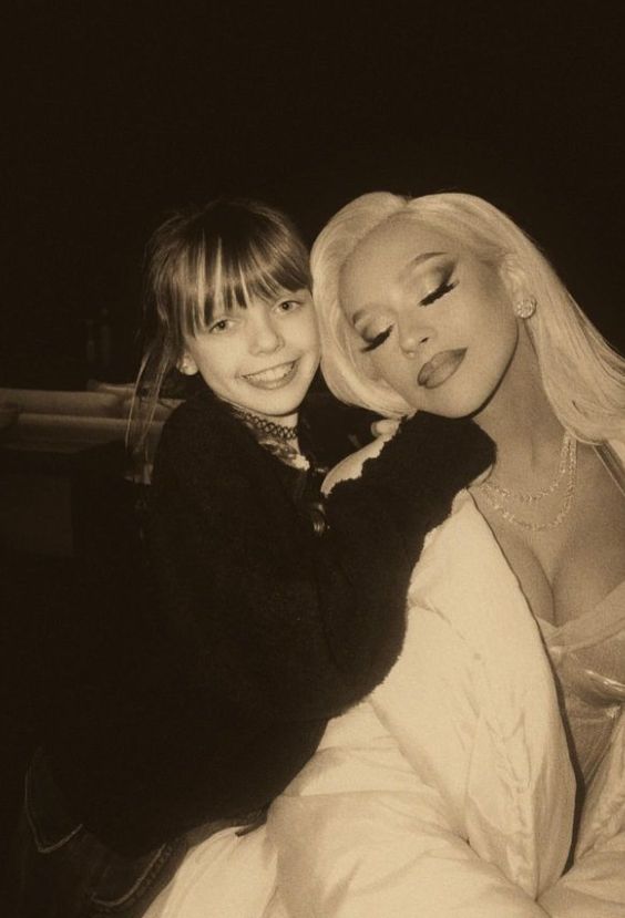 A young girl cuddling up to Christina Aguilera