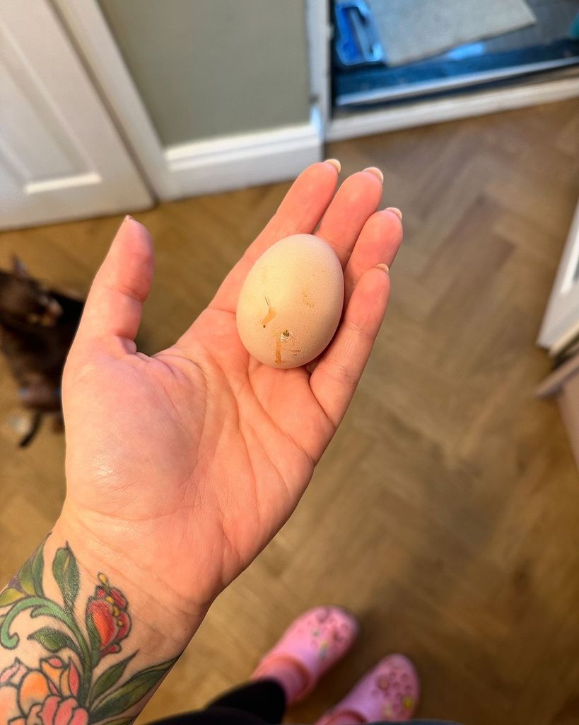 Ellie Warner inside her home holding an egg laid by own chickens